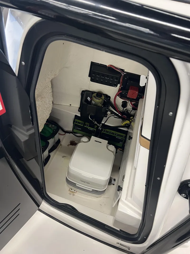 Slide: The Image of 2021 Tidewater 2500 Carolina Bay boat interior with electrical components and portable toilet. - 10