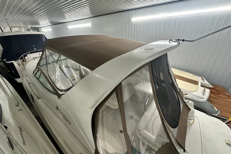 Slide: The Image of 1998 Cruisers Yachts 3075 Rogue in storage, featuring a brown canopy and sleek design. - 17