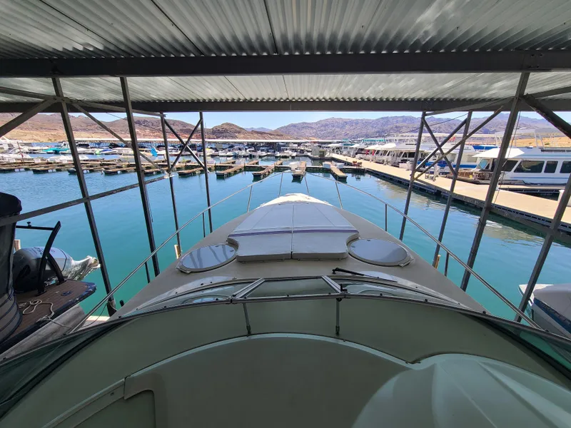 Slide: The Image of 1995 Cruisers Rogue yacht docked in a marina with scenic mountain views. - 11