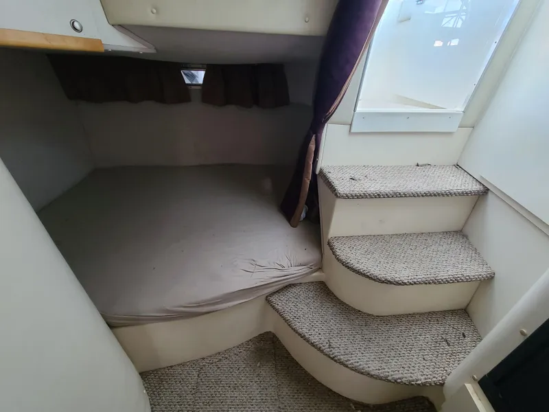 Slide: The Image of 1995 Cruisers Rogue boat interior with bed and carpeted stairs. - 13