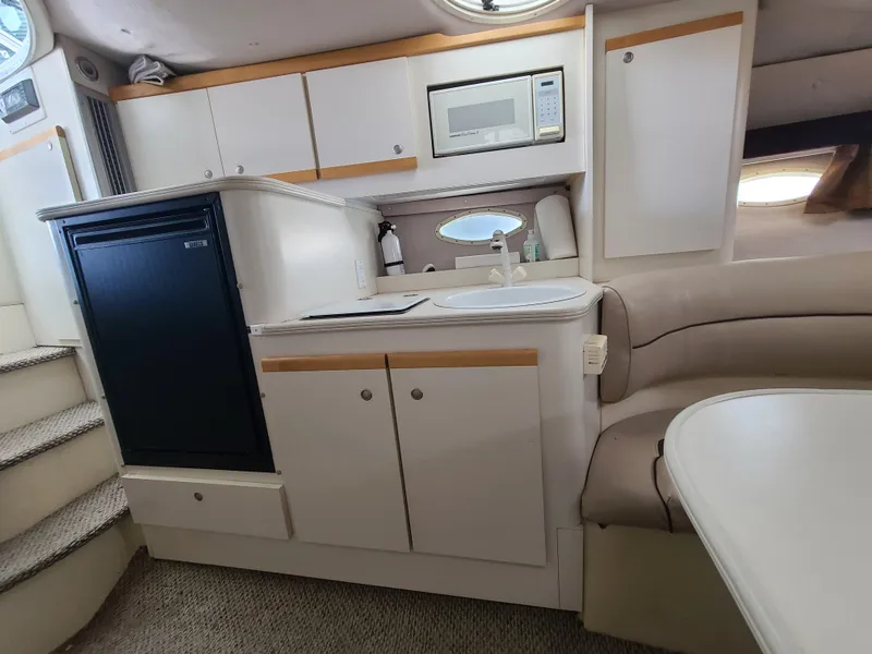 Slide: The Image of 1995 Cruisers Rogue boat interior with kitchenette, microwave, and seating area. - 16