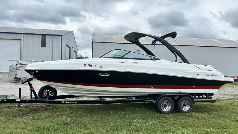Slide: The Image of 2018 Rinker QX29 BR boat on a trailer near industrial buildings. - 3