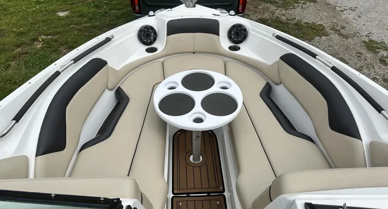 Slide: The Image of 2018 Rinker QX29 BR boat interior with cushioned seating and a round table. - 9