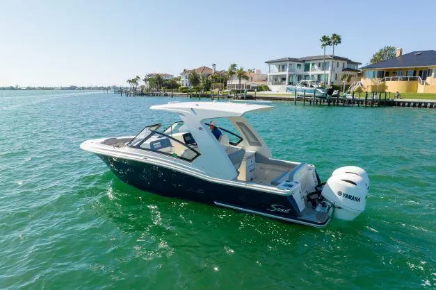 Slide: The Image of 2021 Scout 277 Dorado boat cruising on clear blue water near waterfront homes. - 21
