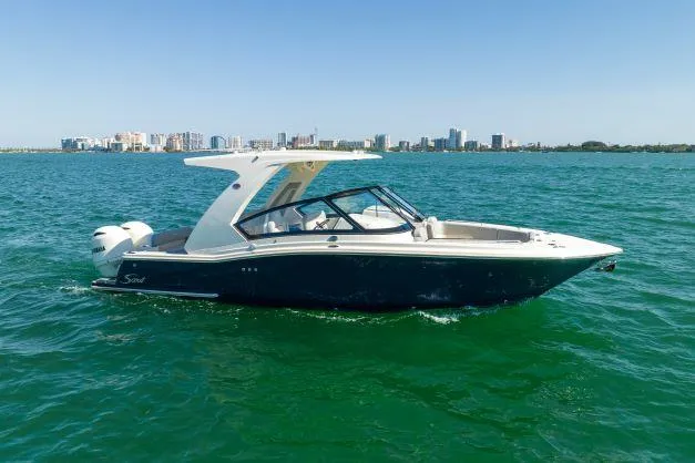Slide: The Image of 2021 Scout 277 Dorado boat cruising on clear blue water with city skyline in the background. - 25