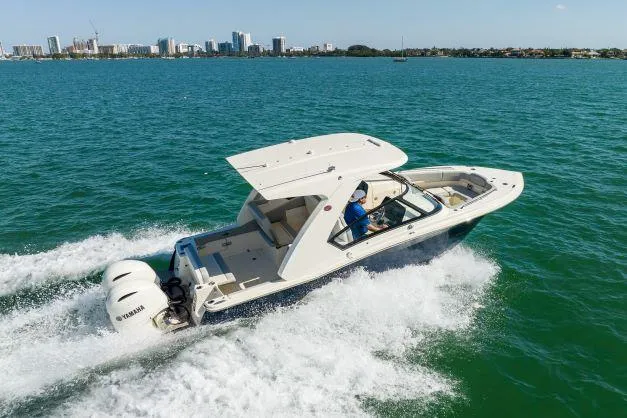 Slide: The Image of 2021 Scout 277 Dorado boat cruising on open water with city skyline in background. - 29