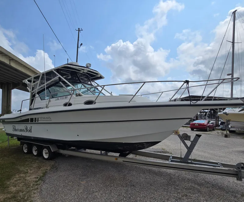 Slide: The Image of 1992 Stamas 288 Liberty boat on trailer under cloudy sky. - 0