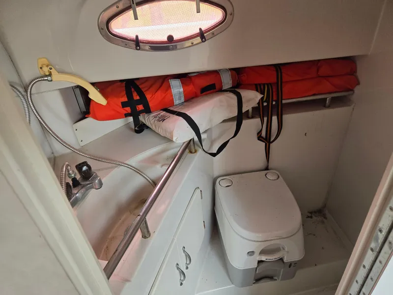 Slide: The Image of 1992 Stamas 288 Liberty boat bathroom with sink, portable toilet, and life jackets. - 10