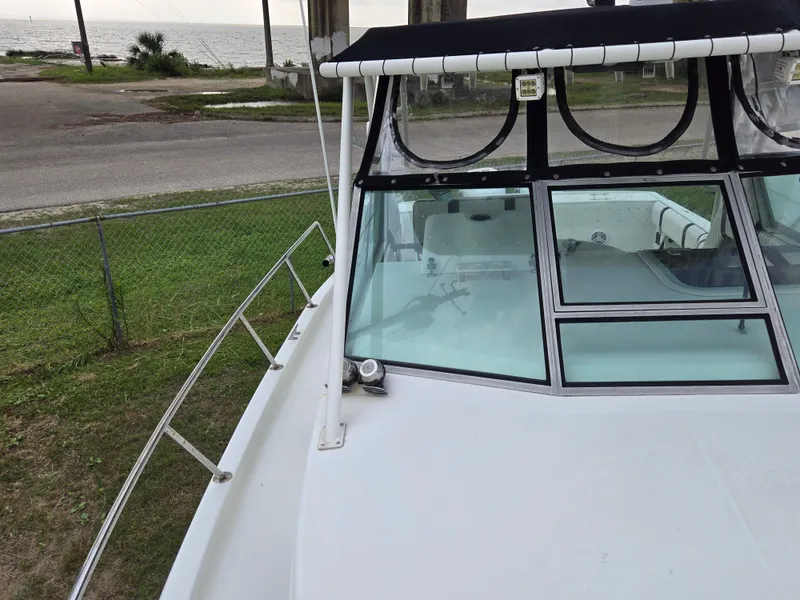 Slide: The Image of 1992 Stamas 288 Liberty boat with windshield and railing, parked near a coastal road. - 27