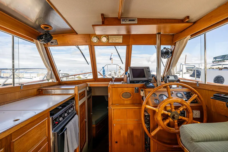 Slide: The Image of 1990 Grand Banks Sedan interior with wooden helm, navigation equipment, and galley. - 13