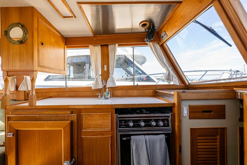 Slide: The Image of Interior of a 1990 Grand Banks Sedan yacht with wooden cabinetry and kitchen area. - 14