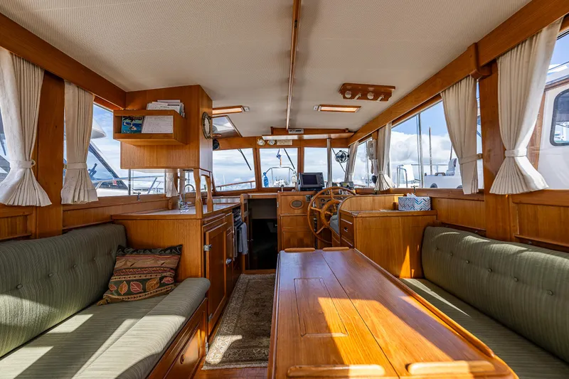 Slide: The Image of Interior of a 1990 Grand Banks Sedan yacht with wooden furnishings and green seating. - 15