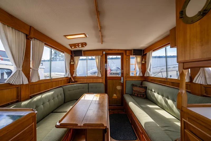 Slide: The Image of Interior of a 1990 Grand Banks Sedan with wooden furnishings and green cushioned seating. - 16