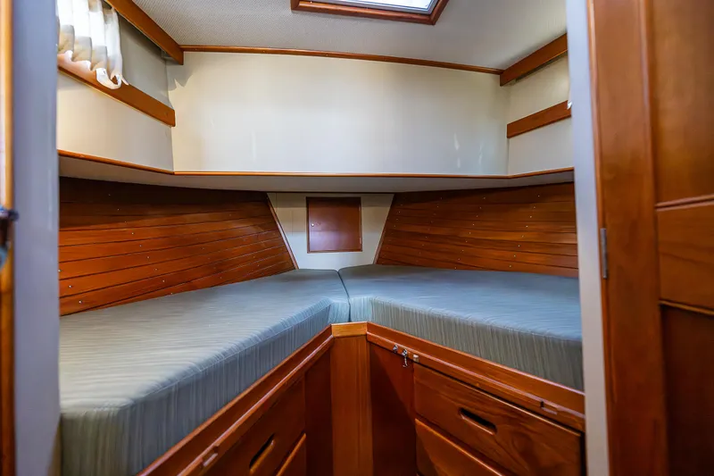 Slide: The Image of 1990 Grand Banks Sedan interior cabin with twin beds and wooden cabinetry. - 19