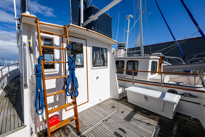 Slide: The Image of 1990 Grand Banks Sedan boat deck with wooden ladder and blue ropes. - 22