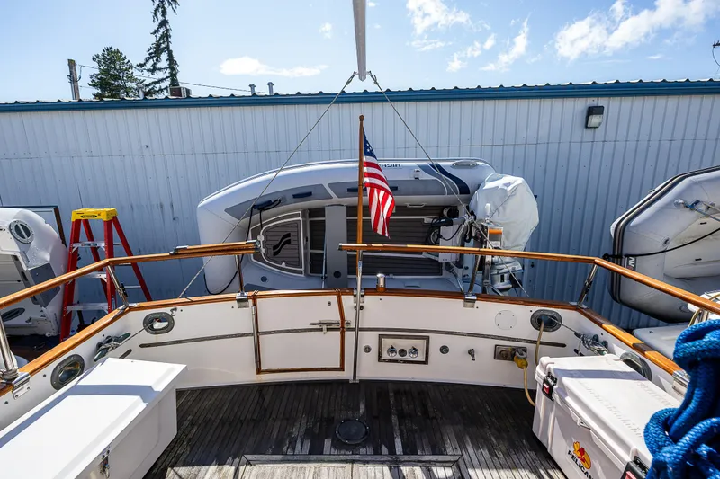 Slide: The Image of 1990 Grand Banks Sedan boat stern view with American flag and docked dinghy. - 23
