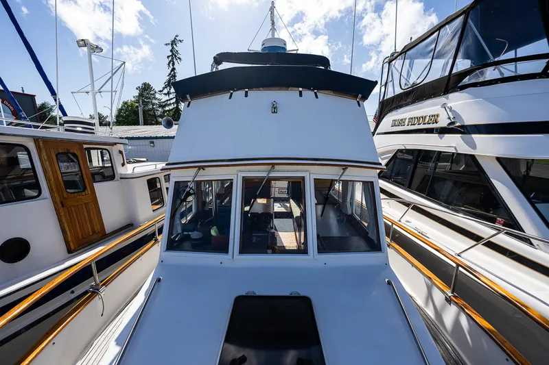 Slide: The Image of 1990 Grand Banks Sedan boat docked between other boats under a sunny sky. - 25
