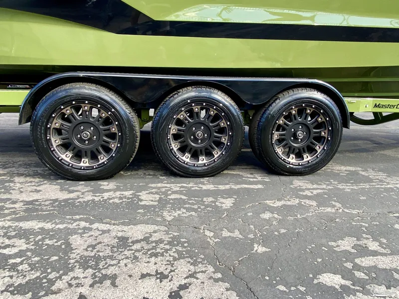 Slide: The Image of 2022 MasterCraft X26 boat trailer with triple axle black alloy wheels. - 19