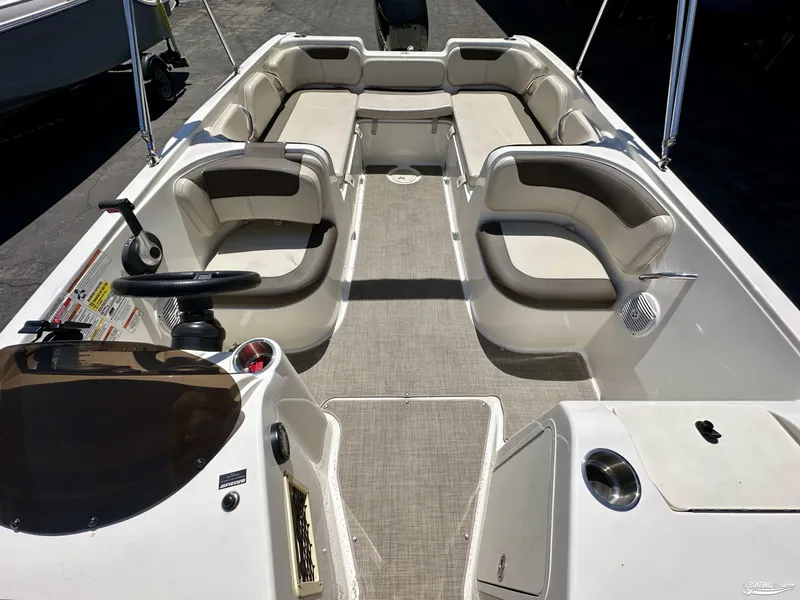 Slide: The Image of 2020 Bayliner E21 boat interior with beige and brown seating, steering console, and cup holders. - 4