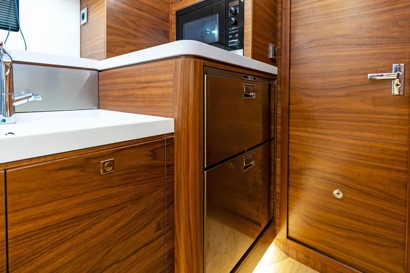 Slide: The Image of Interior of Amel 50 yacht kitchen, wood paneling, sink, and cabinets, year 2019. - 11