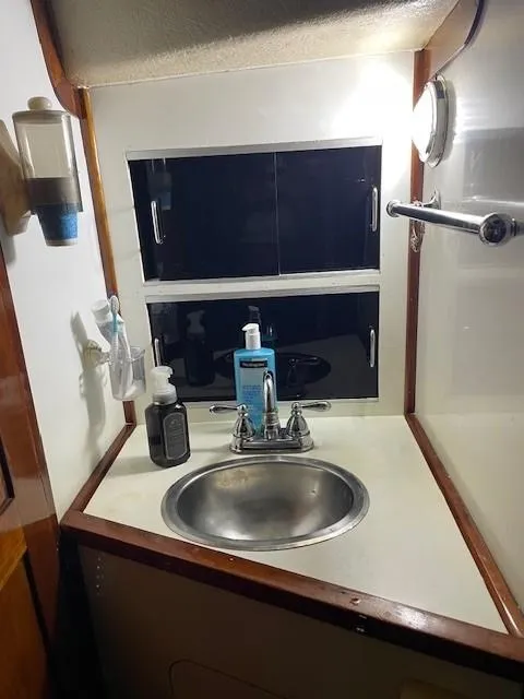 Slide: The Image of 1975 Allied Mistress boat bathroom with sink, toiletries, and storage cabinets. - 11