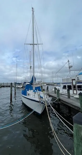 Slide: The Image of 1975 Allied Mistress sailboat docked at a marina on a cloudy day. - 14