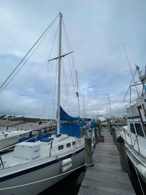 Slide: The Image of 1975 Allied Mistress sailboat docked at a marina under a cloudy sky. - 15