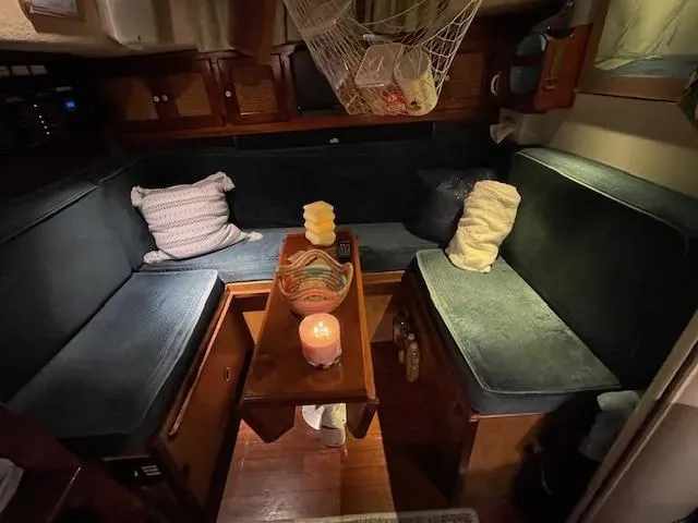 Slide: The Image of Cozy 1975 Allied Mistress sailboat interior with cushions, table, and candlelit ambiance. - 9