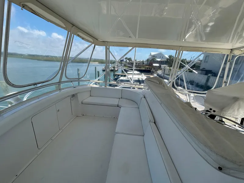 Slide: The Image of Interior view of 1999 Bertram 60 Convertible yacht with white seating and panoramic windows. - 23