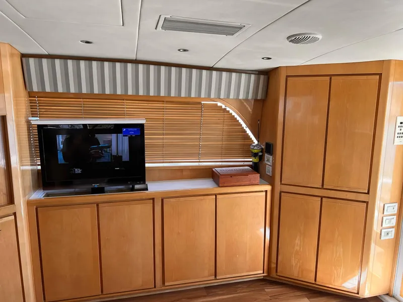 Slide: The Image of Interior of a 1999 Bertram 60 Convertible yacht with wooden cabinets and a TV. - 36