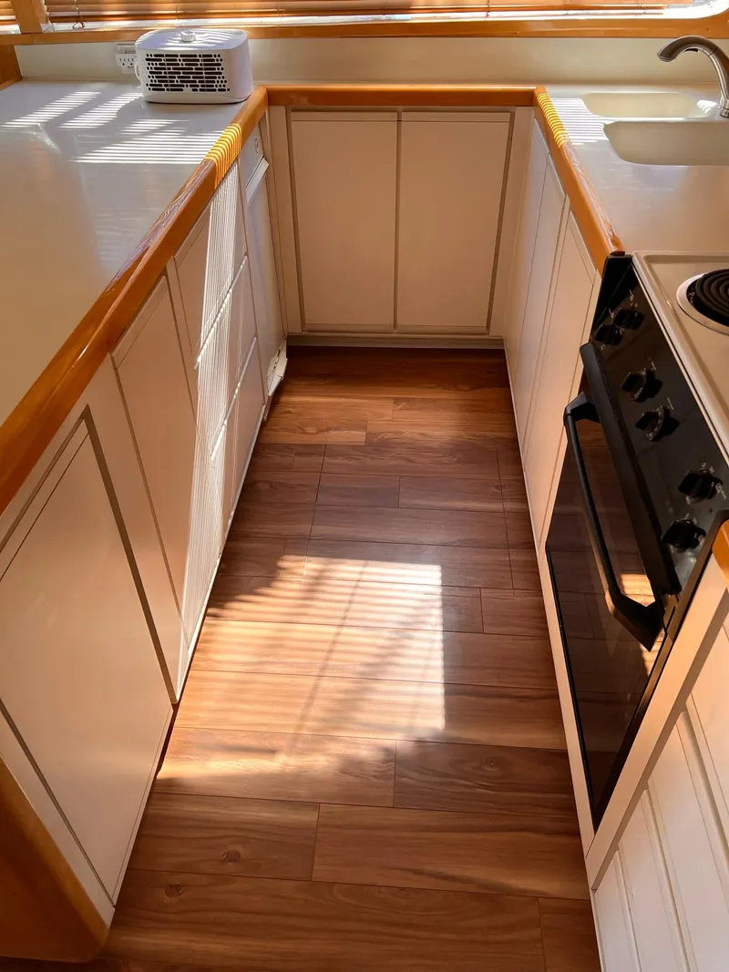 Slide: The Image of Compact kitchen in a 1999 Bertram 60 Convertible yacht with wooden flooring and white cabinetry. - 39