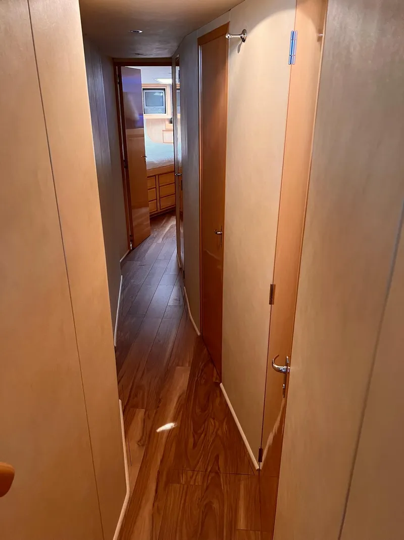 Slide: The Image of Narrow hallway inside a 1999 Bertram 60 Convertible yacht with wooden flooring. - 42