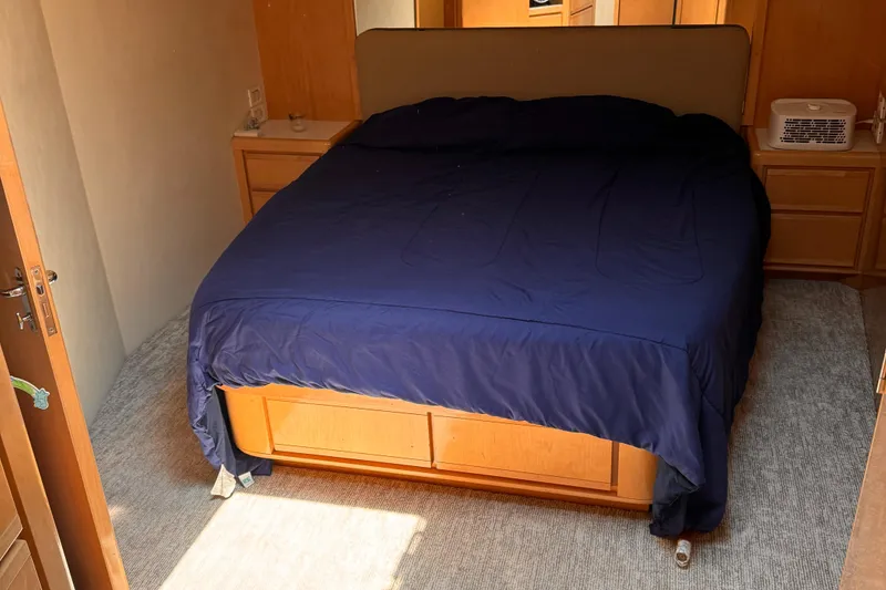 Slide: The Image of 1999 Bertram 60 Convertible bedroom with blue bedding and wooden furniture. - 48