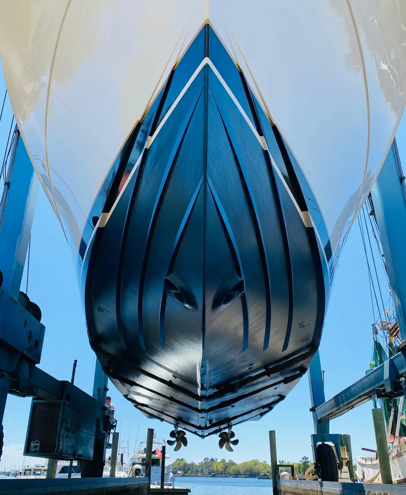 Slide: The Image of 1999 Bertram 60 Convertible yacht in dry dock, showcasing its sleek hull design. - 7