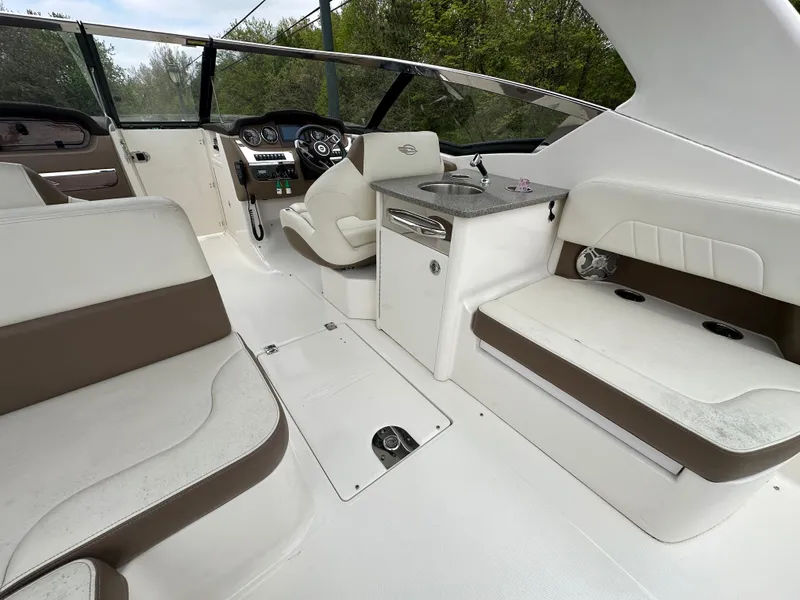 Slide: The Image of Interior of 2014 Chaparral 307 SSX boat with white and brown seating, steering console, and sink. - 18