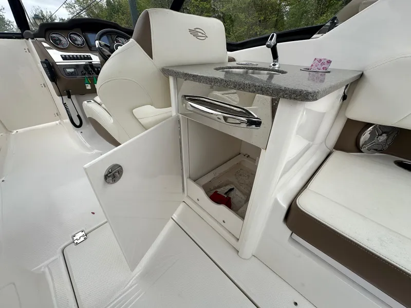 Slide: The Image of 2014 Chaparral 307 SSX boat interior with open storage compartment and helm controls. - 30