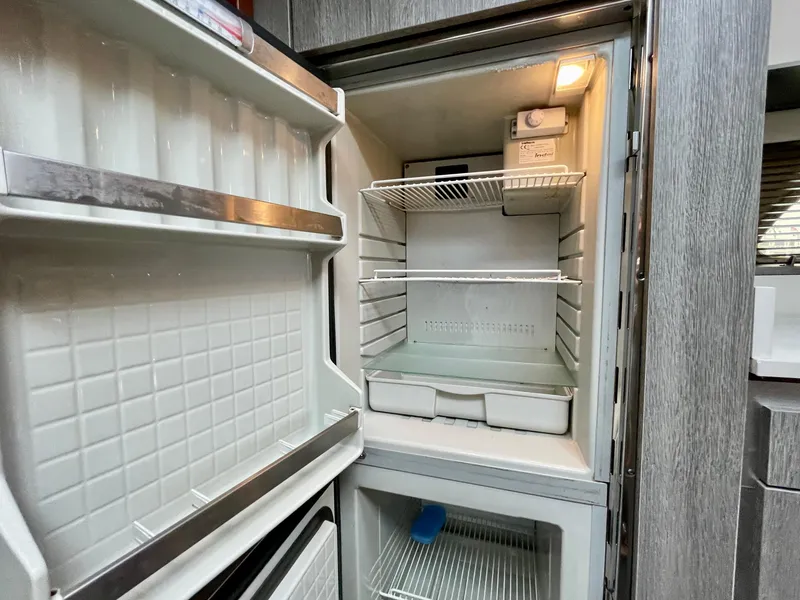 Slide: The Image of Open refrigerator inside a 2009 Sea Ray 470 Sundancer yacht, showing empty shelves and compartments. - 37