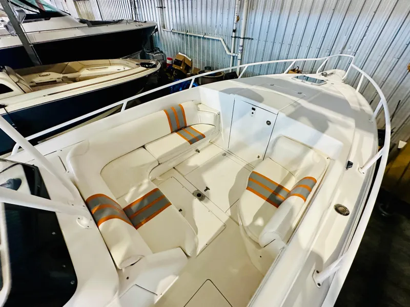 Slide: The Image of 2003 Intrepid 322 Cuddy boat interior with white and orange seating in a storage facility. - 9