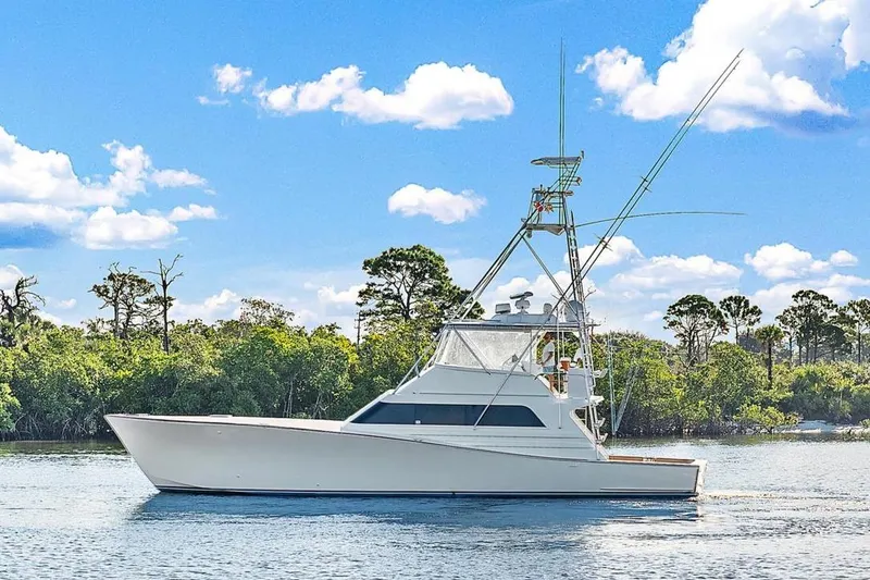 The Image of 1990 Monterey Custom Sportfish boat on calm water with trees in the background. - 0
