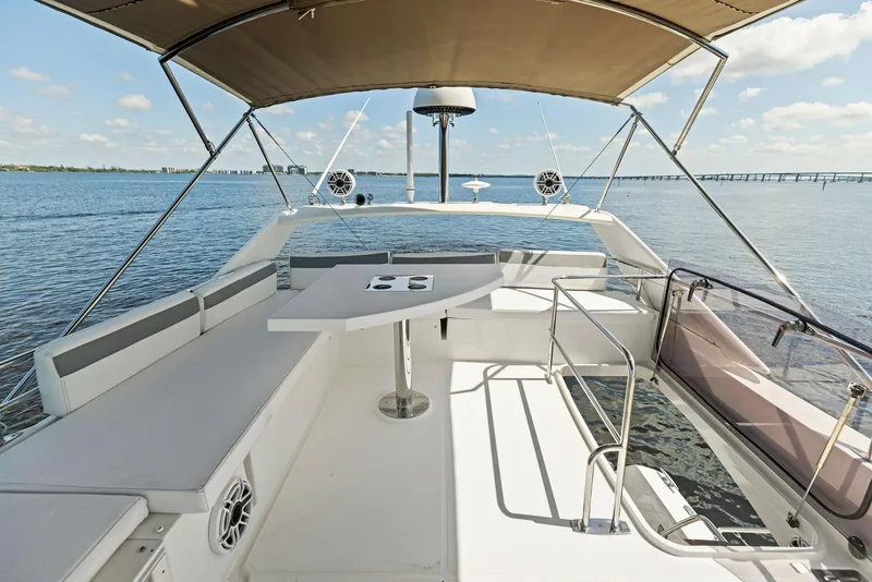 Slide: The Image of 2018 Prestige 460 yacht flybridge with seating and table, overlooking calm waters. - 47
