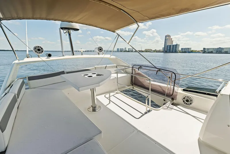 Slide: The Image of 2018 Prestige 460 yacht deck with seating and table, overlooking waterfront cityscape. - 49