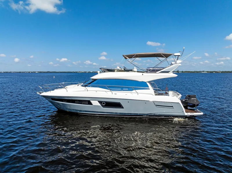 Slide: The Image of 2018 Prestige 460 yacht cruising on open water under a clear blue sky. - 6
