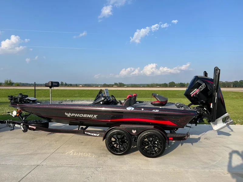 The Image of 2024 Phoenix 20 XE fishing boat on trailer, black and red, parked outdoors. - 1