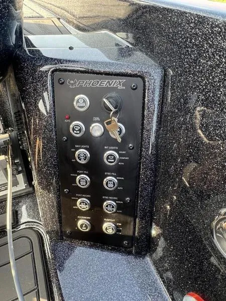 Slide: The Image of Control panel of a 2024 Phoenix 20 XE boat with various switches and key ignition. - 27