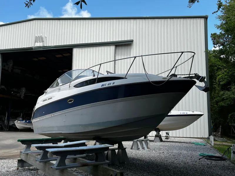 Slide: The Image of 2005 Bayliner 245 boat on stands outside a large storage building. - 1
