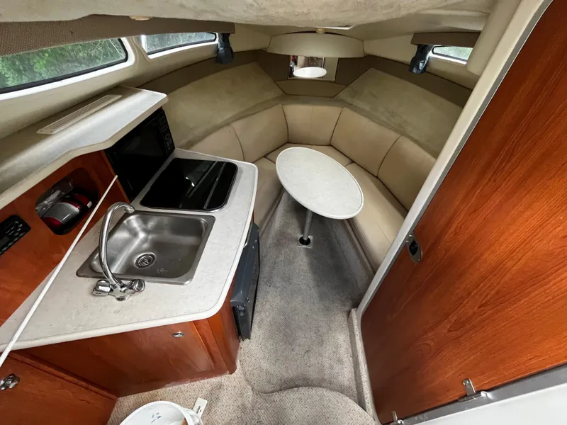 Slide: The Image of 2005 Bayliner 245 cabin interior with kitchenette, sink, and seating area. - 16