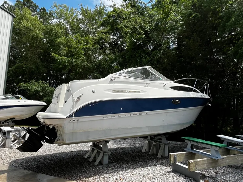 Slide: The Image of 2005 Bayliner 245 boat on stands, surrounded by trees. - 5