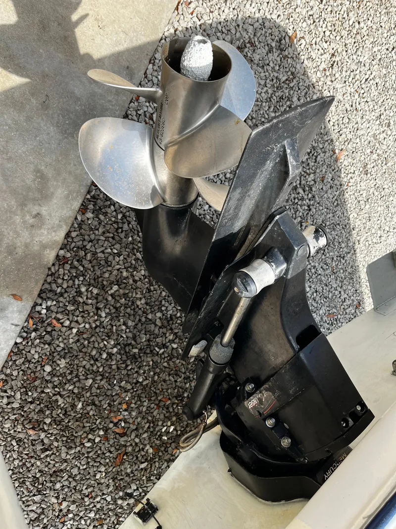 Slide: The Image of 2005 Bayliner 245 boat propeller and outdrive on gravel surface. - 6