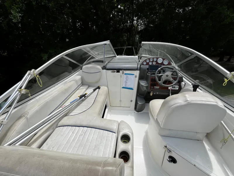 Slide: The Image of 2005 Bayliner 245 boat interior with white seating and steering console. - 8