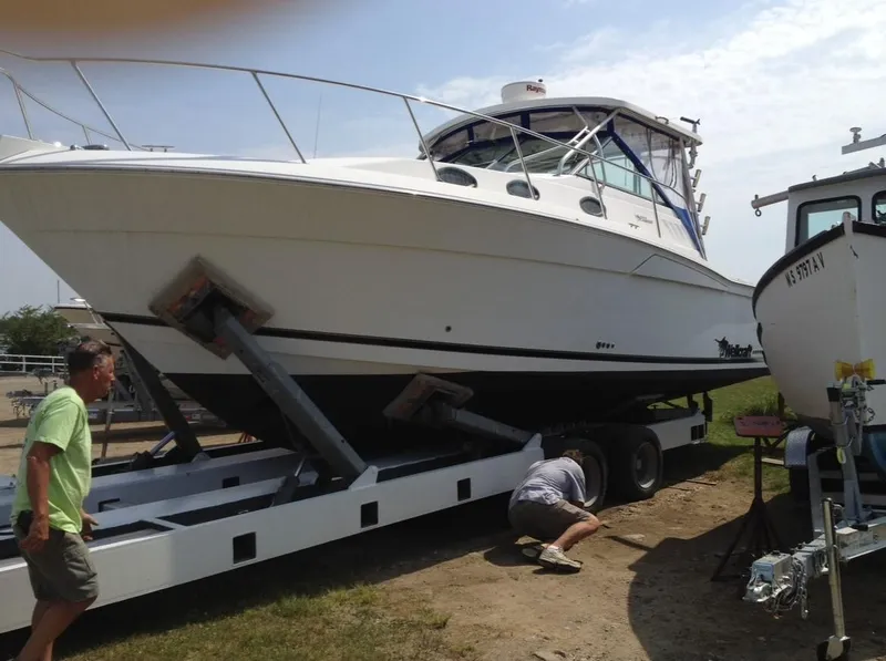 Slide: The Image of 2000 Wellcraft 330 Coastal boat on trailer, with people inspecting it outdoors. - 3